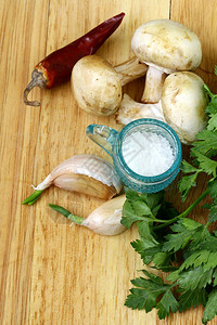 大蒜蘑菇辣椒欧芹黄瓜和切菜板上的香料图片