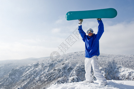 快乐的运动员肖像与站在山顶上的滑雪板图片