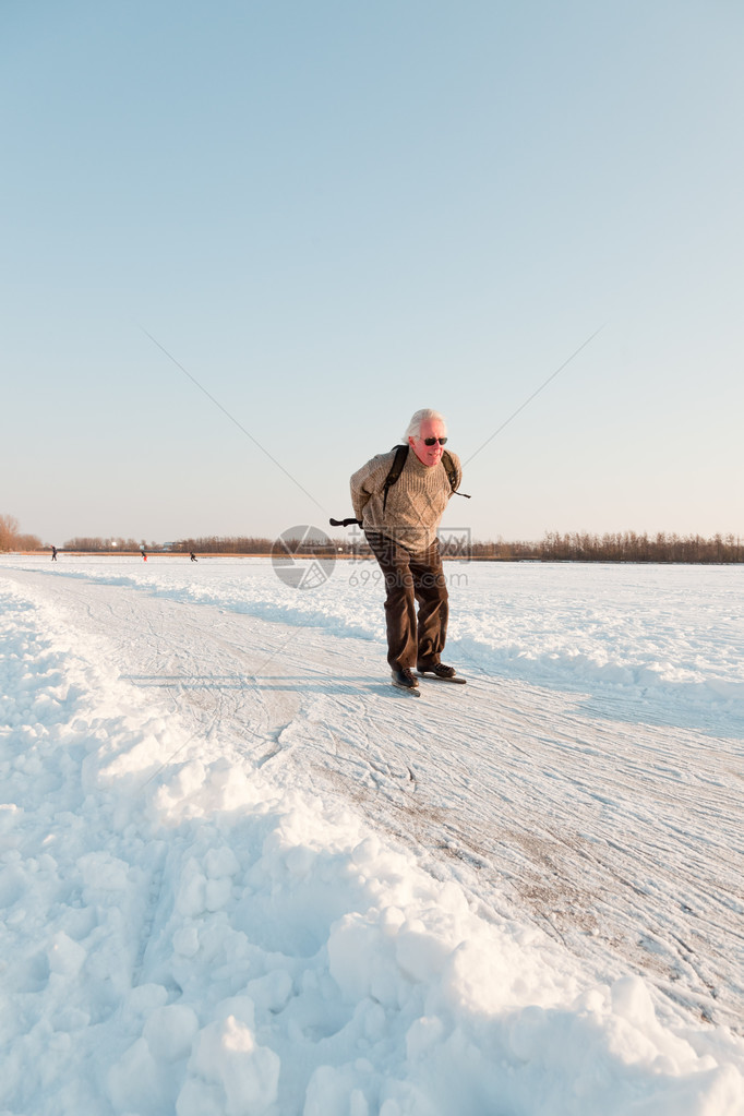 荷兰冬季风景和高级滑冰员在冰冻湖边蓝晴图片