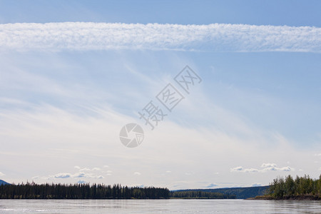 蓝天中的一些夏日云彩在强大的小溪育空河上空图片