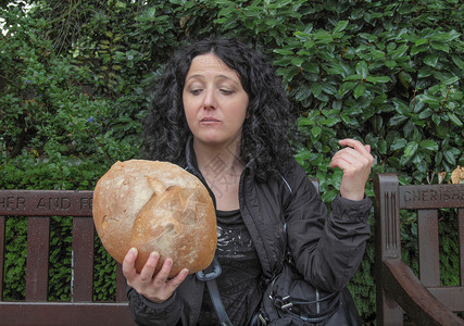 无论吃不美丽的年轻黑发美女的肖像看着巨大的面包在图片