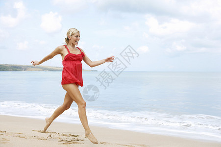 年轻有魅力的女人在金沙滩上奔图片