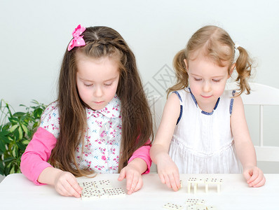 两个小女孩在桌子上玩多米诺骨牌图片