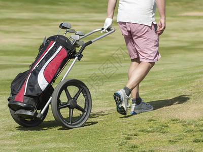 高尔夫球手带着高尔夫球袋和手推图片