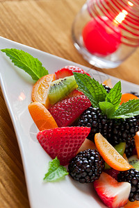 白盘上的新鲜草莓黑莓猕猴桃和金橘的水果沙拉图片