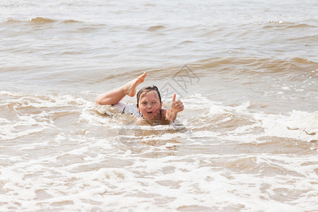 小男孩在海浪中的沙滩上玩耍图片