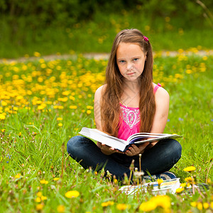 在田野里读书的少女看着镜头图片