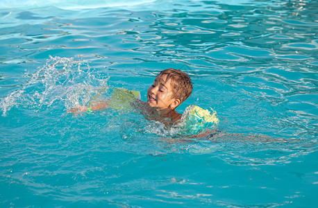小男孩在游泳池里学习游泳图片
