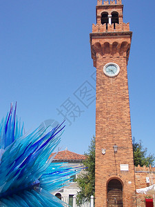 在穆拉诺岛有时钟的楼和蓝色玻璃雕塑图片