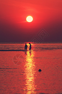 海滩上的红色日落与金色的灯光效果图片