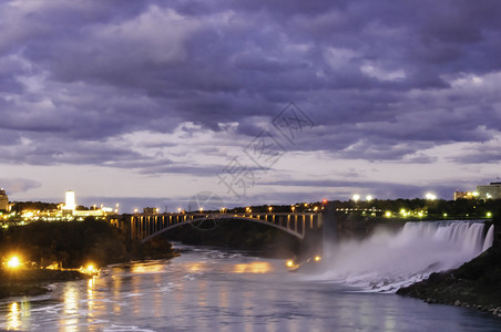 尼亚加拉瀑布在月光下与建筑物和大桥通向美国的背景图片
