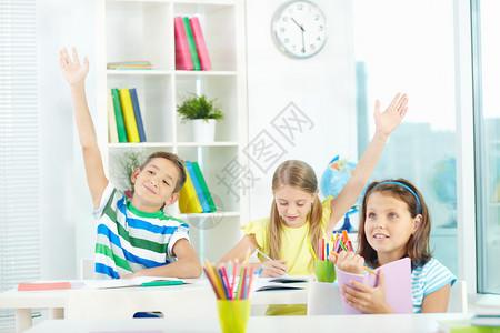 聪明的小学生在工作场所举手与同学一起拉着手的肖图片