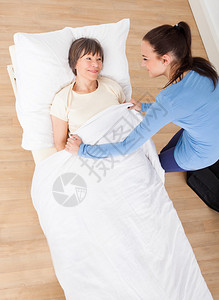 在养老院用毯子照顾年青女护理员图片
