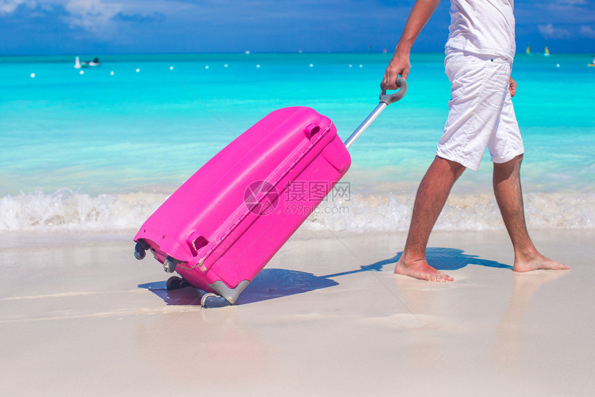 特写一个男人在沙滩上拉行李图片
