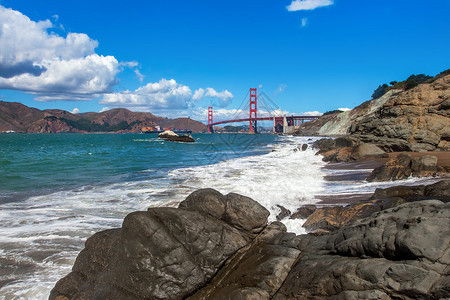 贝克海滩的黑岩石和海浪在美国旧金山作为金门大桥背景图片
