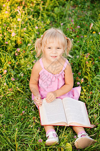 小女孩坐在草地上看书图片