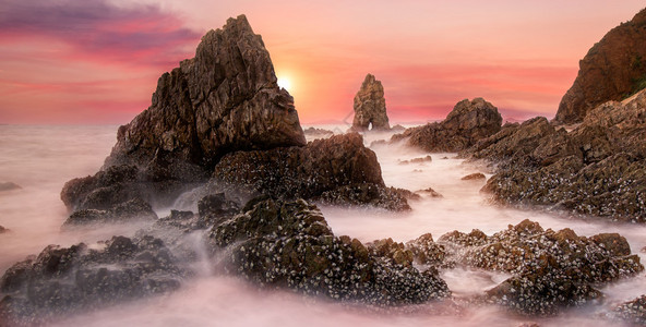 泰国日落时海浪击中岩石图片