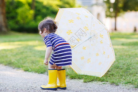 可爱的两年女孩穿着黄雨靴在夏令图片