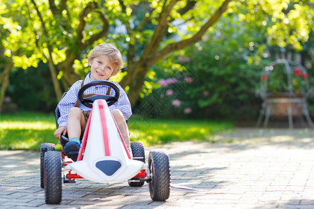 活跃的小男孩夏天花园里开踏板车图片