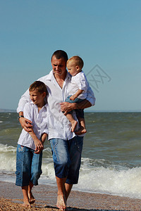 父亲和两个儿子在海滩上握着手在度假图片