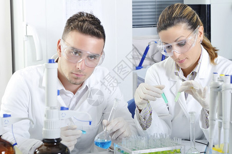 有吸引力的年轻博士生科学家在化学实验室观察溶液蒸馏后蓝色和绿色指示图片