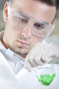 有吸引力的年轻博士生科学家在化学实验室观察溶液蒸馏后的绿色指图片