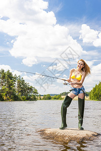 在池塘里钓鱼的年轻女人图片