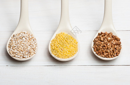白色木桌上的大麦荞麦和小米碎粒图片