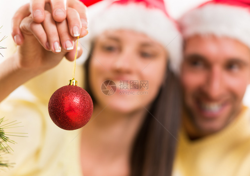 快乐的年轻夫妇在家里享受装饰圣诞树的快乐图片