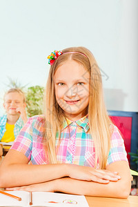 微笑的女孩坐在书桌边手图片