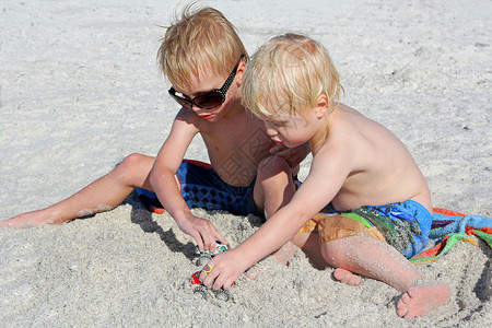 两个小孩在沙滩上玩沙玩具图片