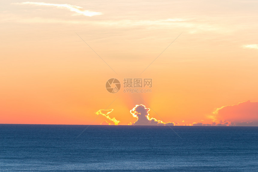 蓝色海平面的云层后面升起的太阳浪漫多彩的天图片