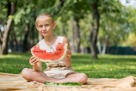 坐在公园里吃西瓜的可爱女孩图片