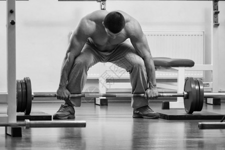 肌肉男在健身房用杠铃锻炼图片