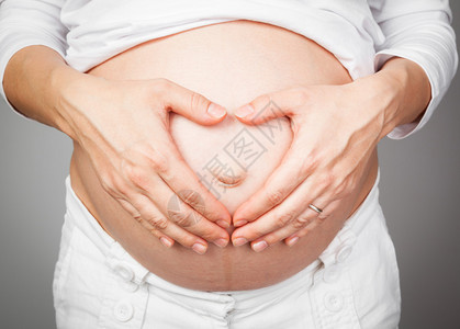 年轻孕妇将手抱在肚子图片