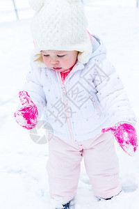 可爱的蹒跚学步的孩子在新雪中玩耍图片