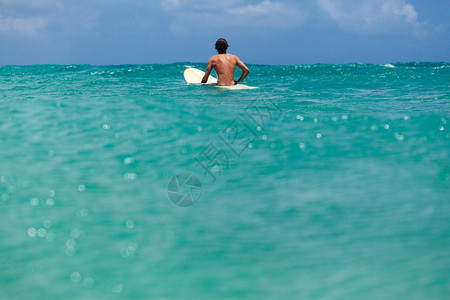 不明身份男子在冲浪中等待海浪在蓝色图片