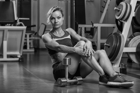 英俊而强壮的健美运动员女人在健身房展示她的肌肉图片