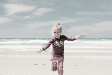 可爱的4岁女孩在海边逃离海浪图片