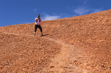 一名年轻女子在犹他州峡谷地区的红峡谷为摄影师拍摄引人注目图片