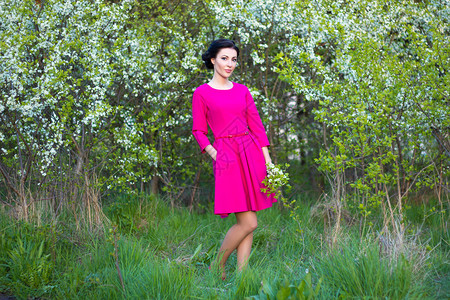 在盛开的春樱花园里穿着粉红色裙子的美丽图片
