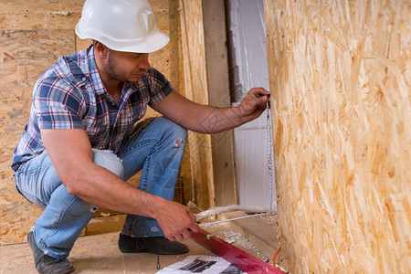 男建筑工人建筑工人头戴白色安全帽测量门框图片