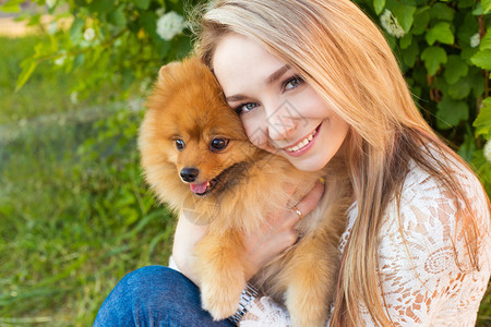 快乐的美丽温柔女孩拥抱着她的宠物狗红图片