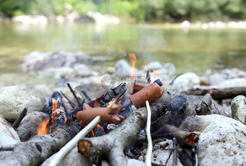 在山河边煮肉和香肠的户外篝火图片