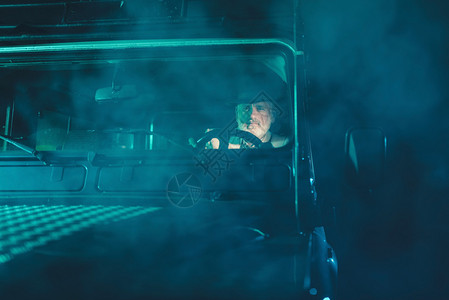 严重的胡子老人驾驶他的老四轮车回家在模糊的黑暗之夜图片