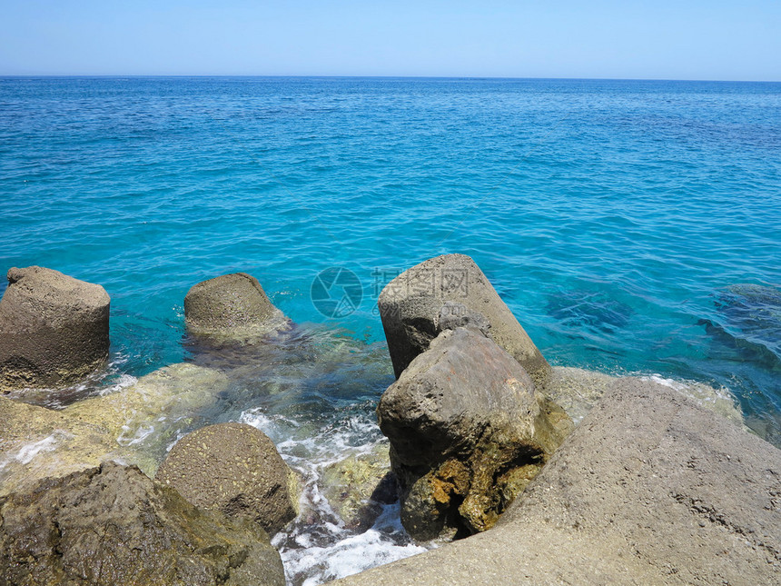 阳光明媚的夏日清澈的海水和棕色岩图片