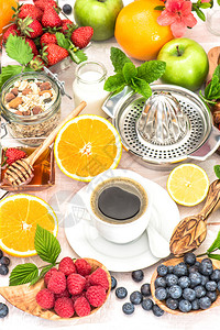 早餐桌设置有咖啡羊角面包麦片格兰诺拉麦片蜂蜜新鲜浆果水果橙苹果牛奶图片
