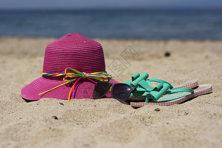 夏季粉色帽子和绿宝石的翻滚在沙滩图片