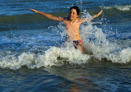 夏天小男孩在波涛汹涌的海浪中飞溅图片