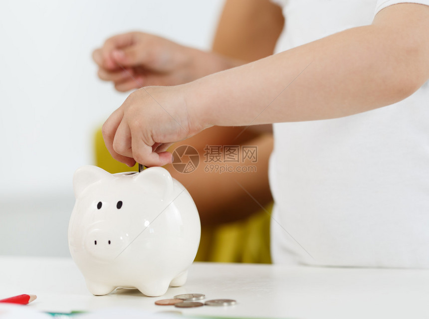 儿童手把零钱硬币放入白色存钱罐槽预算费用概念使储蓄和有效的投资理念未来需要押图片
